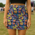 High-waisted bodycon mini skirt with an allover print of rainbow monarch butterflies and colorful tropical flowers on a dark background. Soft, stretchy poly-spandex fabric hugs the body for a flattering fit. Styled for rave, Y2K, and festival outfits. Sizes XS to XL.